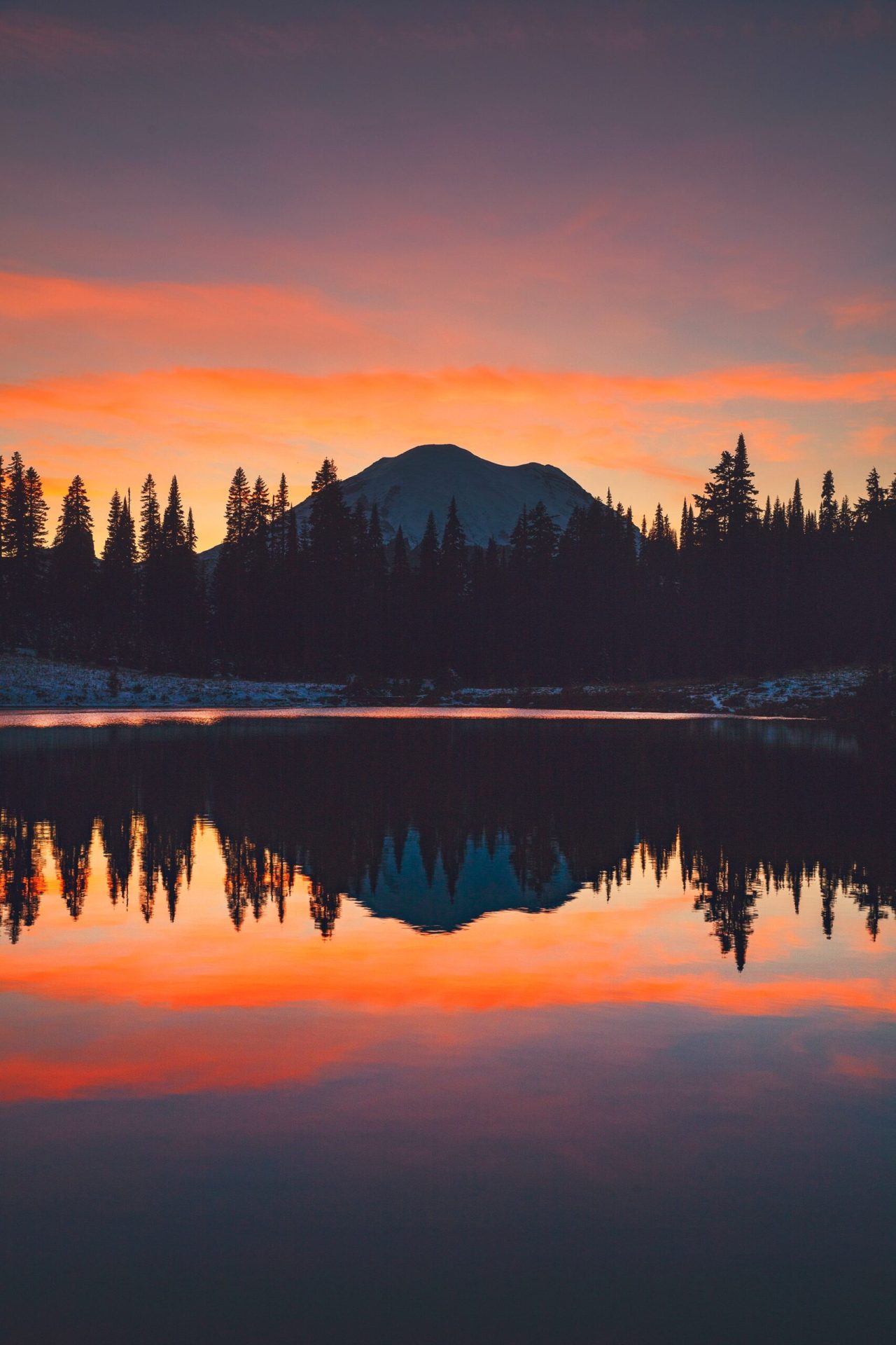 sunset image of trees and a mountain reflected in a lake